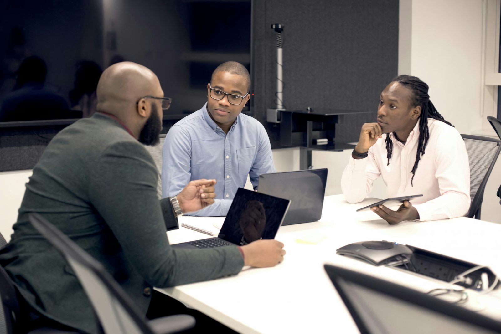 Three professionals in a meeting with laptops